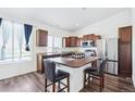 Bright kitchen with wooden cabinetry, stainless steel appliances, island seating and a large window at 5571 Killarney St, Denver, CO 80249