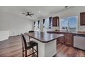 Open-concept eat-in kitchen with stainless steel appliances, granite countertops, and island seating with ceiling fan at 5571 Killarney St, Denver, CO 80249