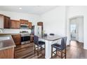 Modern kitchen features stainless steel appliances, wood cabinets, and an island with bar seating at 5571 Killarney St, Denver, CO 80249