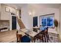 Modern dining room with hardwood floors, glass table, and open staircase at 2697 S Deframe Cir, Lakewood, CO 80228