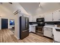 Well-lit kitchen featuring stainless steel appliances, white cabinets and a view of the front door at 2697 S Deframe Cir, Lakewood, CO 80228