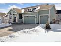 Lovely exterior view of a home featuring a three-car garage, covered porch, and well-maintained landscaping in winter at 1030 W Hopkins Dr, Elizabeth, CO 80107