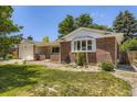View of a brick home with a well-kept lawn and a covered front porch at 649 Nucla Way, Aurora, CO 80011