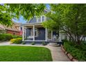 Inviting blue home featuring a cozy porch swing, lush green lawn, and mature shade tree for relaxed outdoor enjoyment at 5675 S Crocker St, Littleton, CO 80120