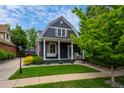 Charming blue home with inviting porch swing, lush lawn, and mature tree at 5675 S Crocker St, Littleton, CO 80120