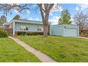 View of single story home and green lawn with mature tree in the front yard on a sunny day at 1420 E Bates Ave, Englewood, CO 80113