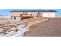 Rear view of a ranch home with a deck, attached garage, and a gravel driveway at 11100 Haskell Creek Rd, Larkspur, CO 80118