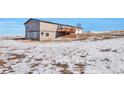 Side view of a ranch home with a deck, attached garage, and snowy yard at 11100 Haskell Creek Rd, Larkspur, CO 80118