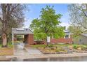 Beautiful home featuring solar panels, a brick exterior, attached carport, and lush front yard landscaping at 3379 W Wagon Trail Dr, Englewood, CO 80110