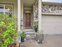 Inviting front porch with a decorative wreath, potted plants, and a stone accent wall at 22466 E Layton Cir, Aurora, CO 80015
