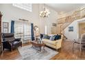 Bright living room with hardwood floors, a grand chandelier, and an open staircase at 11274 W 54Th Ln, Arvada, CO 80002