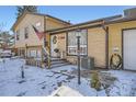 Charming home featuring a covered porch, a decorative front door, and a well-manicured front yard with snow at 1599 S Telluride St, Aurora, CO 80017