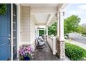 Inviting front porch with seating, stone pillars and view of neighborhood at 6032 Umber St, Arvada, CO 80403