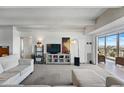 Bright living room with large TV, shelving, and balcony access with views of the surrounding landscape at 7877 E Mississippi Ave # 1008, Denver, CO 80247
