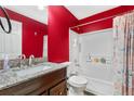 Bathroom with red accent wall, granite counter, and tub shower combo at 13664 Linden Ct, Thornton, CO 80602
