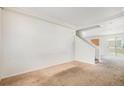 Spacious living room featuring neutral carpeting, crown molding, and staircase access to the upper level at 20108 Randolph Pl, Denver, CO 80249