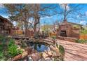 An inviting backyard features a stone fireplace, pond, and mature trees creating a serene outdoor oasis at 11545 Quivas Way, Westminster, CO 80234