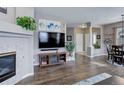 Spacious living room with hardwood floors, fireplace, TV, and view of dining area at 3993 S Dillon Way # 104, Aurora, CO 80014