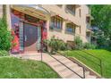 Building entrance with concrete steps and metal railings, a red facade accent, and manicured landscaping at 1000 E 8Th Ave # 4, Denver, CO 80218