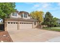 Three-car garage with ample driveway space, complemented by a well-maintained lawn and mature trees at 9432 La Quinta Way, Lone Tree, CO 80124