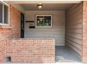 A covered porch with brick accents, a small window, and the house number displayed above the mailbox at 945 Emerald St, Broomfield, CO 80020