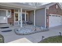 Inviting covered front porch with seating area, decorative rock garden, and a cozy ambiance at 7160 S Jellison St, Littleton, CO 80128