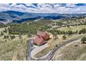 Breathtaking aerial view of a secluded log home with mountain views, winding driveway, and surrounding natural landscape at 401 Raptor Point Rd, Golden, CO 80403