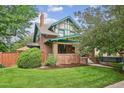 Charming two-story home featuring a brick facade, green trim, a well-manicured lawn, and mature trees at 2201 Cherry St, Denver, CO 80207