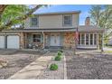 Inviting two-story home with a charming brick facade, tidy landscaping, and an American flag at 18263 E Mansfield Ave, Aurora, CO 80013