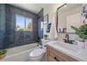 Stylish bathroom with blue tiled shower, white vanity, and modern fixtures at 3206 Elizabeth St, Denver, CO 80205