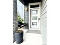 Inviting front porch featuring a modern door, hanging chair, and a large pot with colorful flowers at 6792 Canosa St, Denver, CO 80221