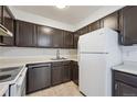 Functional kitchen featuring dark wood cabinets, stainless steel appliances, and neutral countertops at 12037 E Harvard Ave # 104, Aurora, CO 80014