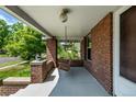 Relaxing covered front porch featuring a wooden swing and brick support columns with a view of the neighborhood at 4654 Bryant St, Denver, CO 80211