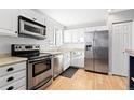 Updated kitchen featuring stainless steel appliances, white cabinetry, and hardwood floors at 1811 S Norfolk St, Aurora, CO 80017