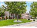 Well-maintained front yard with green lawn, mature trees, decorative rock, and a two-car garage home at 18027 E Ida Dr, Centennial, CO 80015