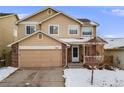 Charming two-story home with a two-car garage and a cozy front porch, surrounded by a snow-covered yard at 4821 N Silverlace Dr, Castle Rock, CO 80109