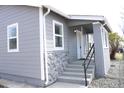 Inviting covered front porch featuring concrete steps, dark metal railing, rock facade, and light gray siding at 4460 Columbine St, Denver, CO 80216