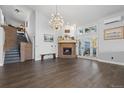 Open living room boasts dark hardwood floors, a brick fireplace, and a stunning chandelier at 11039 Roxborough Dr, Littleton, CO 80125