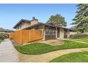 Home featuring a wood fence, tidy landscaping, and a well-maintained exterior at 3827 S Fraser St, Aurora, CO 80014