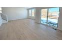 Bright living room with light hardwood floors and sliding glass doors to backyard at 241 Paloma Way, Elizabeth, CO 80107