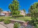 Landscaped side yard with a stone retaining wall and a variety of plants and greenery at 3531 E 91St Ave, Thornton, CO 80229