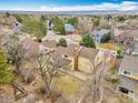 Expansive aerial view showcases a yellow home nestled among mature trees in a neighborhood with mountain views in the distance at 10627 Chautauga Mtn, Littleton, CO 80127