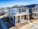 Inviting two-story home featuring a second-story balcony, gray siding and a bright red front door at 46554 Avery Ln, Bennett, CO 80022