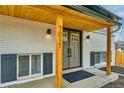 Close up of covered front porch with wood detail and freshly painted white brick at 7017 W 62Nd Pl, Arvada, CO 80003
