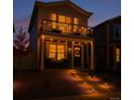 Charming home with a welcoming front porch, balcony and well-lit walkway at dusk at 5027 N Walden Way, Denver, CO 80249