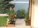 Charming front porch featuring lush landscaping and comfortable chair with decorative plants and an American Flag at 7492 W Cedar Cir, Lakewood, CO 80226