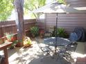 Inviting outdoor patio with dining set, umbrella, and cozy seating area with colorful potted plants at 7492 W Cedar Cir, Lakewood, CO 80226