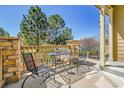 Cozy patio with metal furniture, stone columns, and serene views of lush greenery and blue skies at 720 Reid Pl, Castle Rock, CO 80108