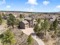 An aerial view showing the home's location in a scenic area, surrounded by trees, and a long driveway at 18750 Spring Valley Rd, Monument, CO 80132