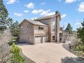 View of home featuring a two-car garage, elevated deck and inviting staircase at 18750 Spring Valley Rd, Monument, CO 80132